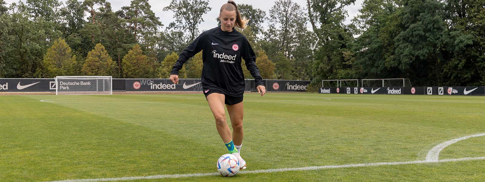 Sécurisez vos chevilles, dribblez encore mieux : notre Sports Ankle Support au football Footballeuse avec des bandages de cheville dribble avec un ballon au pied sur un terrain en gazon