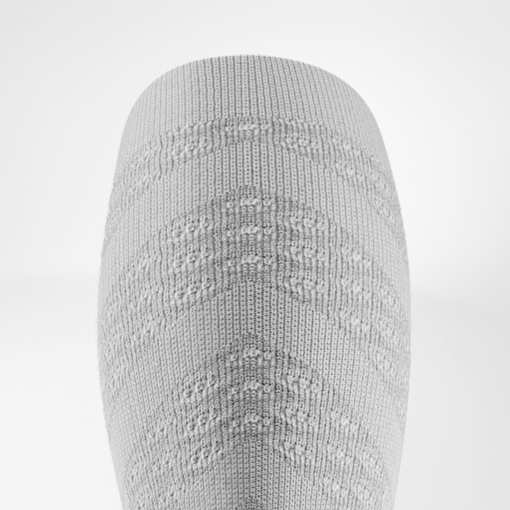 Weiße Leichtigkeit auf jedem Kilometer Detailansicht eines weißen Compression Sleeves mit strukturierter Oberfläche, die gezielten Druck auf die Wadenmuskulatur ausübt.