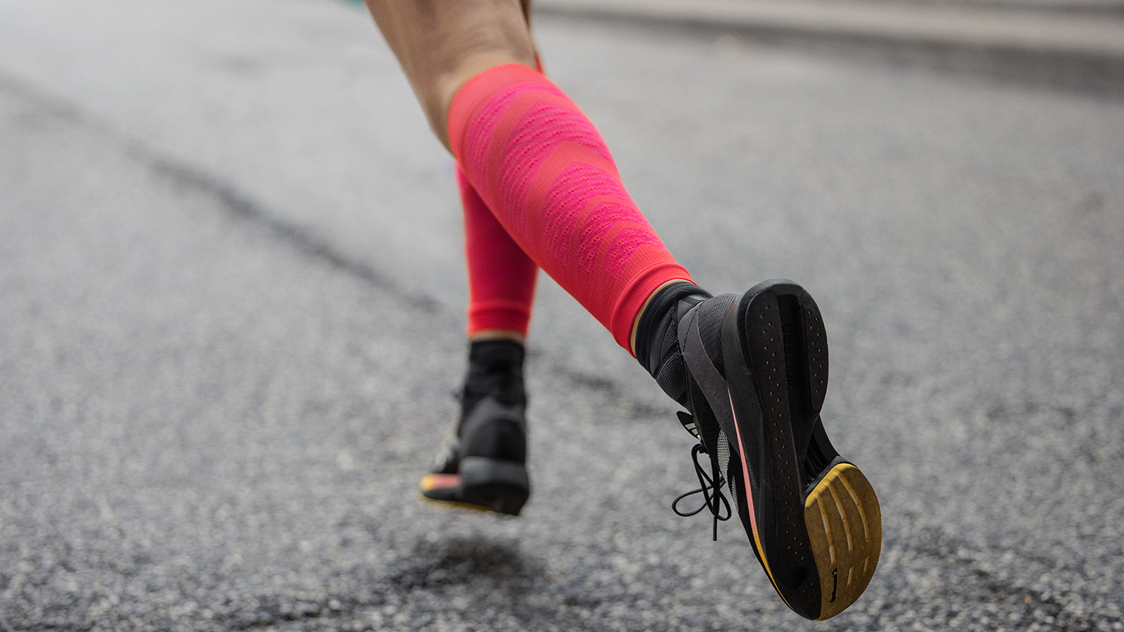 Waden eines Läufers mit grau-blau Laufsocken von hinten