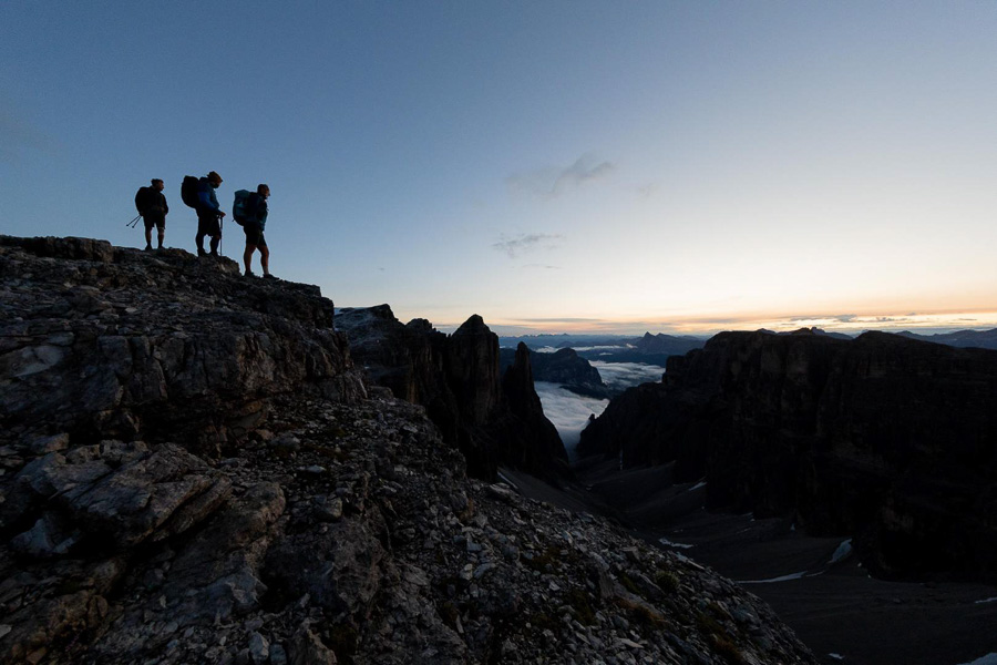 Wanderer auf einem Berggipfel in den Dolomiten bei Sonnenaufgang Silhouetten von Wanderern auf einem Berggipfel in den Dolomiten bei Sonnenaufgang oder Sonnenuntergang. Im Hintergrund sind Wolken und Bergspitzen zu sehen.