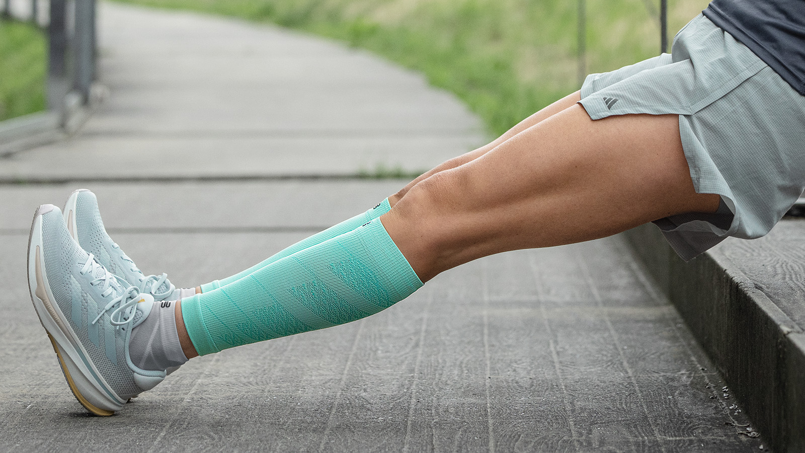 S'étirer après la course peut favoriser la régénération, surtout après des séances d'entraînement marathon plus longues Coureuse en chaussettes de course roses étire ses mollets assise au sol et sourit