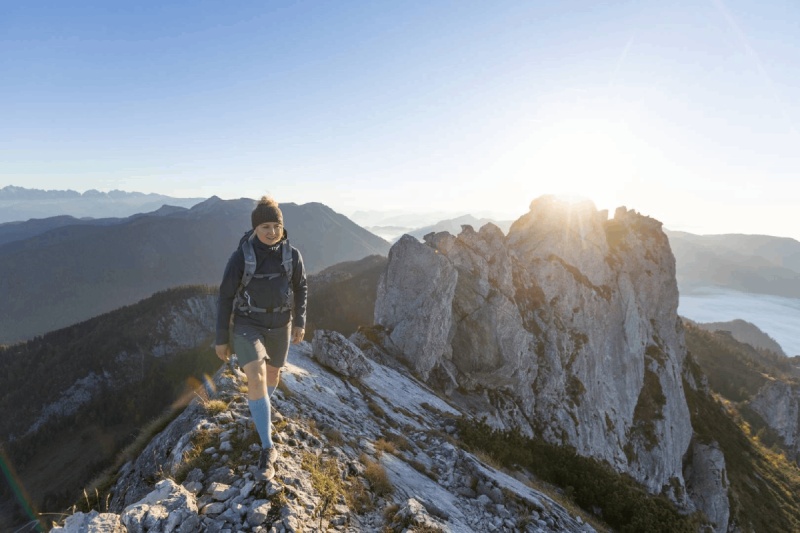 Wanderer auf Berg mit offenen Armen beim Sonnenuntergang
