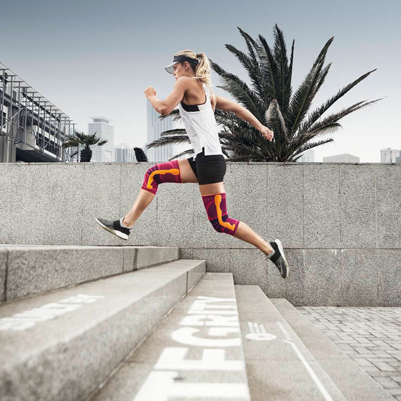 Knee Support rose lors de la course Une coureuse saute avec une genouillère par-dessus des escaliers en ville