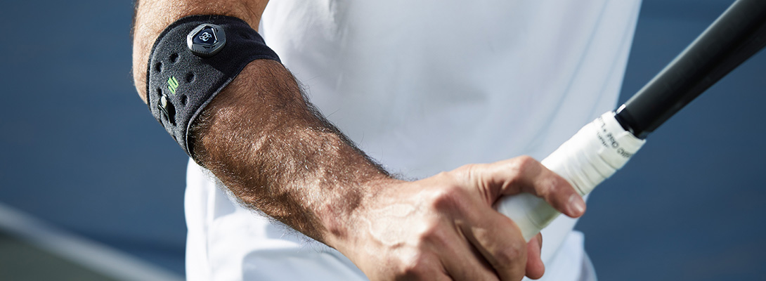 Ellenbogenbandage beim Tennis Tennisspieler der eine Ellenbogenspange zur Entlastung bei Tennisellenbogen trägt