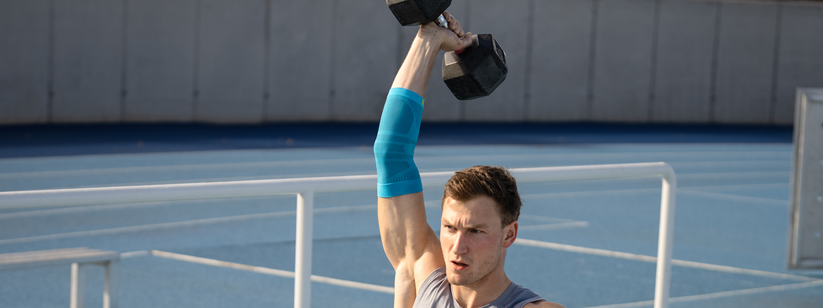 Bande de coude pendant l'entraînement de fitness Thoms Röhler tient un poids en l'air et stabilise son bras à l'aide d'une bande de coude
