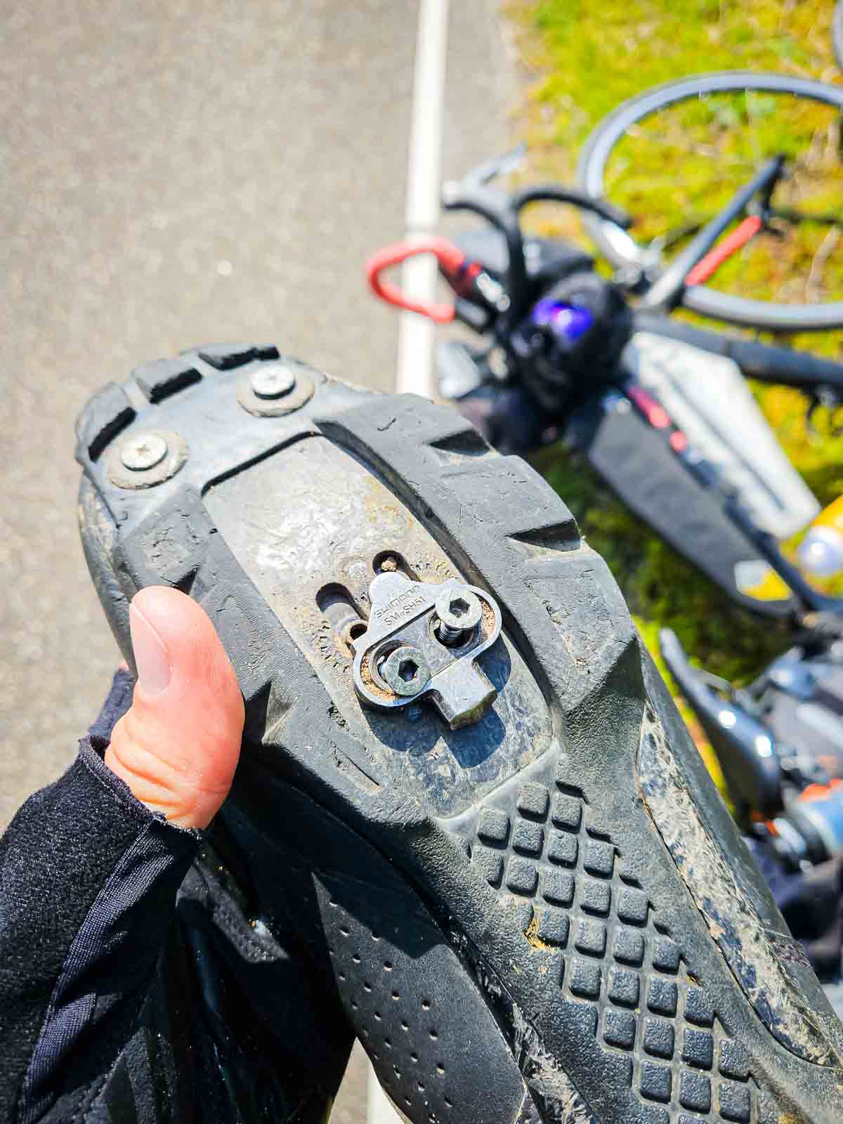 Chaussure de vélo vue de dessous avec des vis lâches sur la cale Une plaque de cale desserrée avec des vis lâches sur une chaussure de vélo