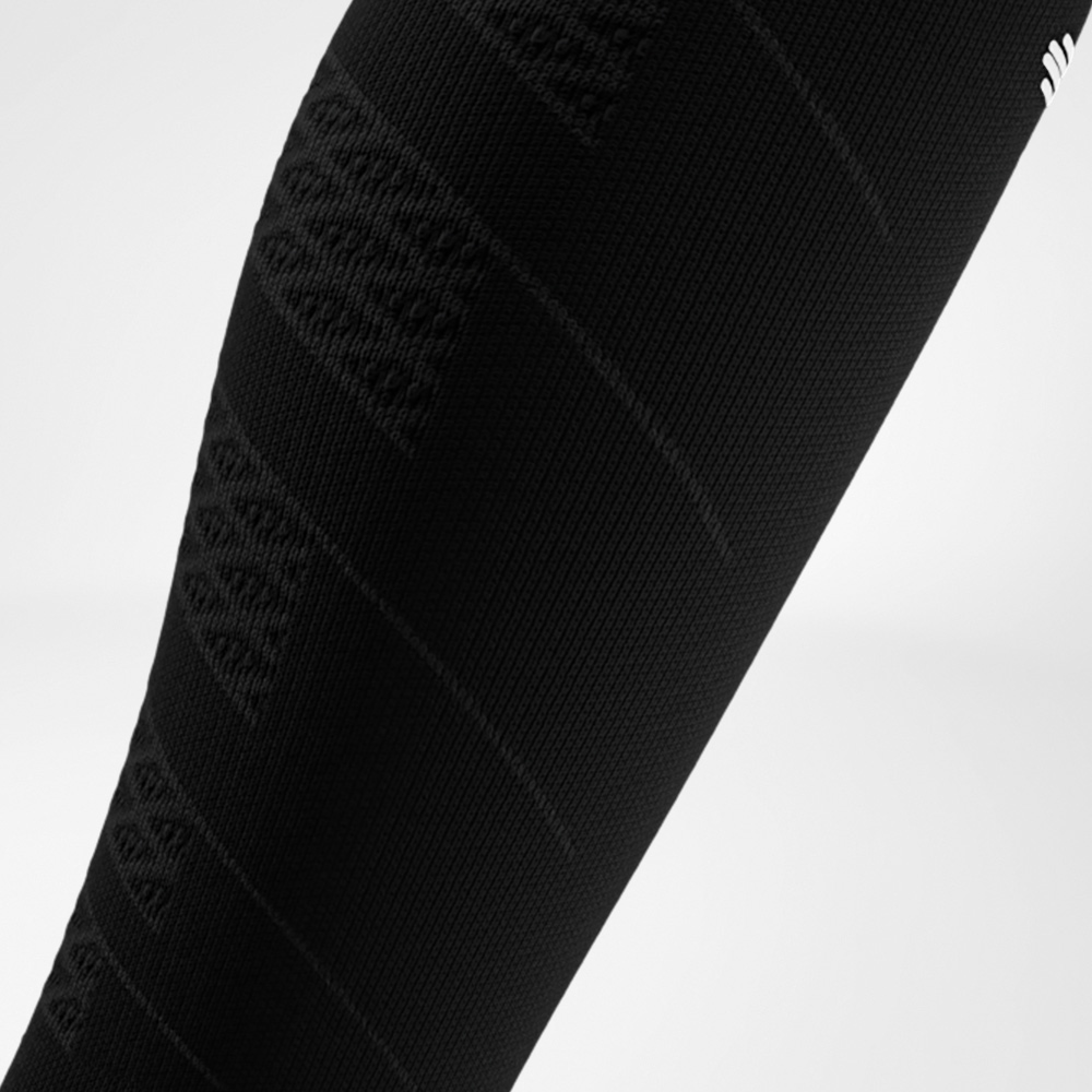 Kraft in Schwarz – dein Kompressions-Boost beim Laufen Nahaufnahme eines schwarzen Run Performance Compression Sleeves am Unterschenkel, das durch die feine Strickstruktur gezielte Kompression bietet und die Wadenmuskulatur beim Laufen unterstützt.