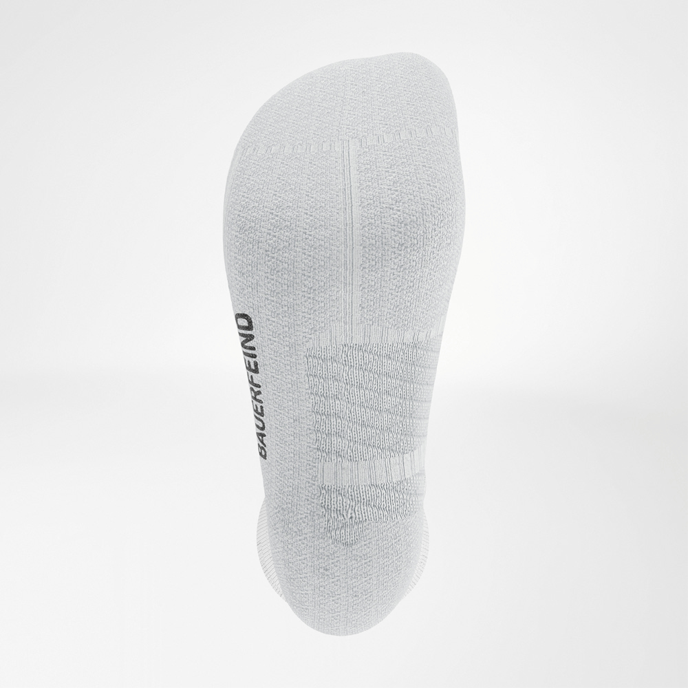 Die gepolsterte Sohle sorgt für festen Halt bei jedem Schritt. Nahaufnahme der Fußsohle der weißen Run Performance Socks von Bauerfeind mit sichtbarer Polsterung und eingestricktem BAUERFEIND-Logo.