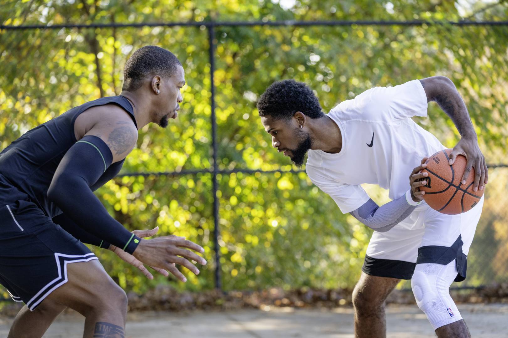 Un joueur de streetball en tenue blanche et bandage en duel Un joueur de streetball en tenue blanche essaie de dribbler son adversaire en tenue noire