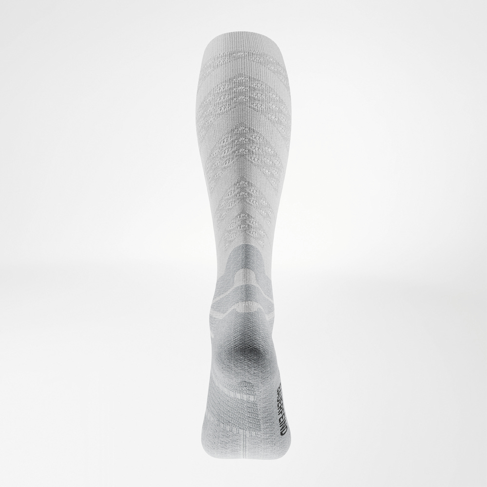 Kompression mit Wirkung – sichtbar bis zur Ferse. Rückansicht der weißen Run Performance Socks Long mit markanter Wadenstruktur und eingestricktem Bauerfeind-Schriftzug an der Ferse.