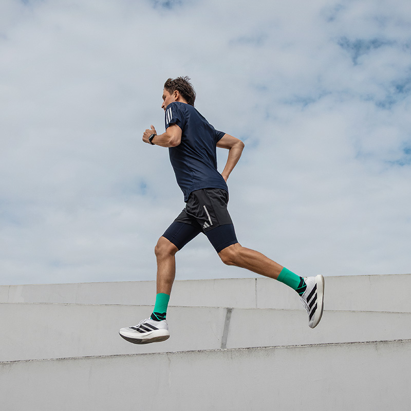 Run Performance Compression Socks blue Mann rennt in einer Stadt neben einem modernen Museum