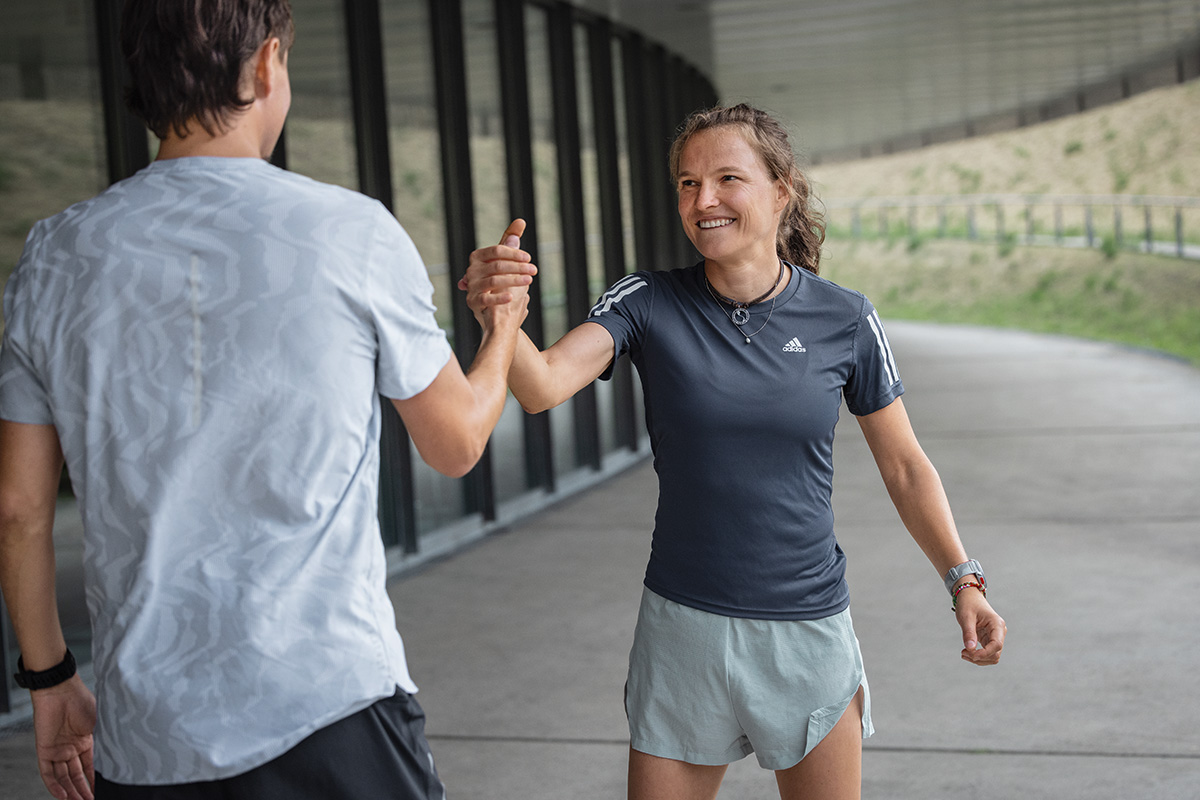 Surtout lors d'un entraînement marathon éprouvant, il est important de simplement profiter tranquillement du coucher de soleil Femme en tenue de course estivale assise par terre, regardant le coucher de soleil