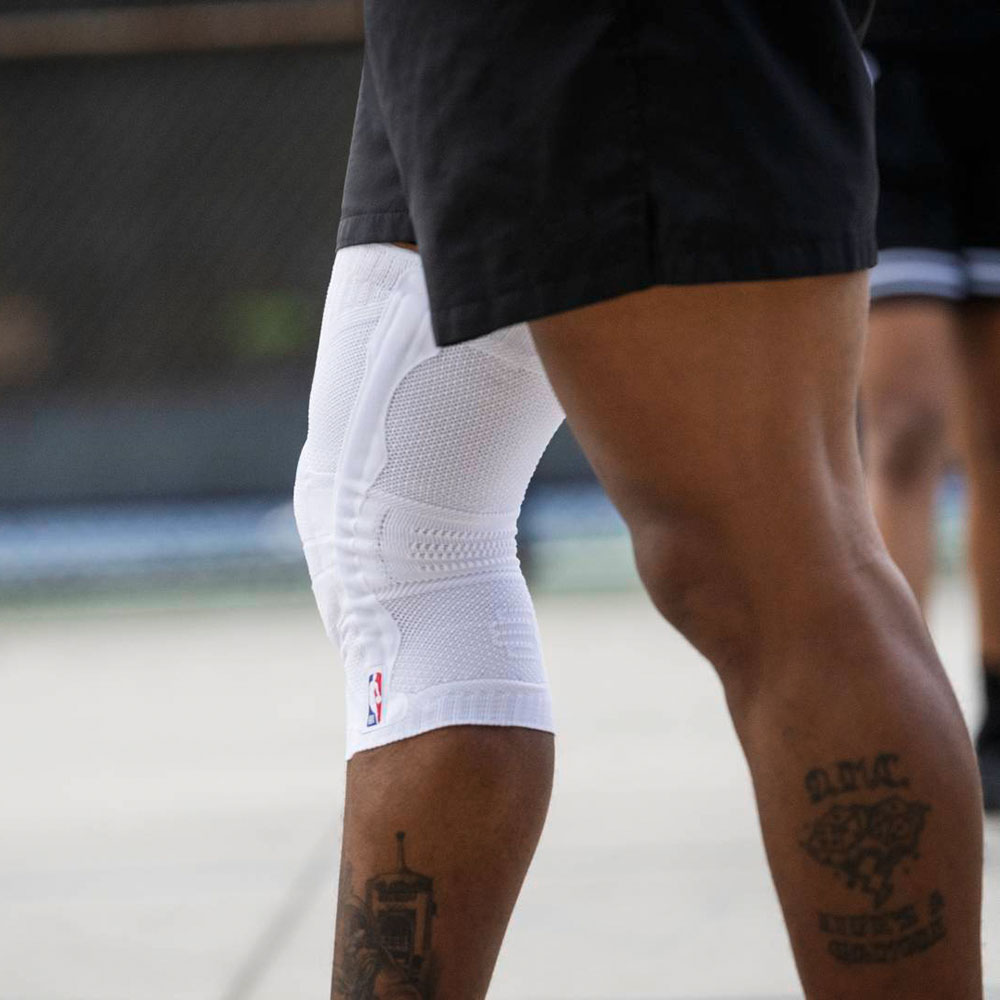 Extrait d'un joueur de basketball avec un bandage au genou blanc portant le logo NBA
