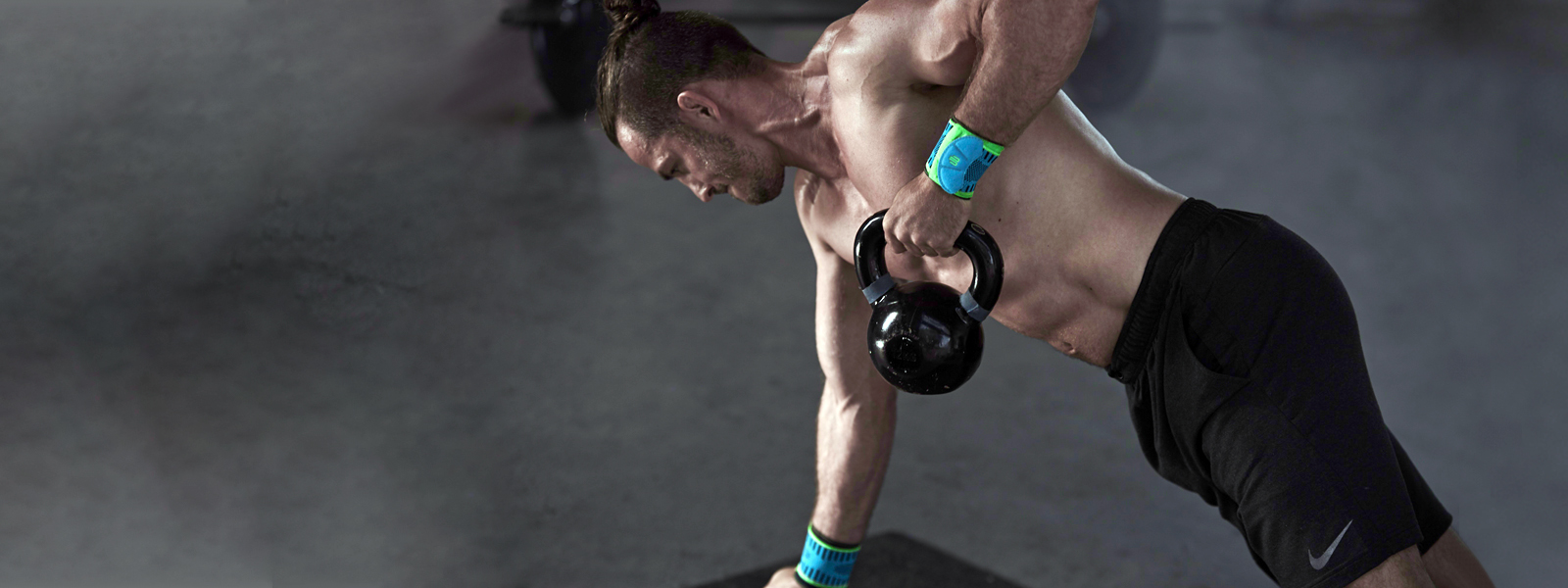 Entraînement avec kettlebell - encore plus puissant avec le Sports Wrist Strap Homme athlétique torse nu avec des bandages au poignet fait de l'exercice avec le kettlebell, une main s'appuie, l'autre tire le kettlebell vers le haut
