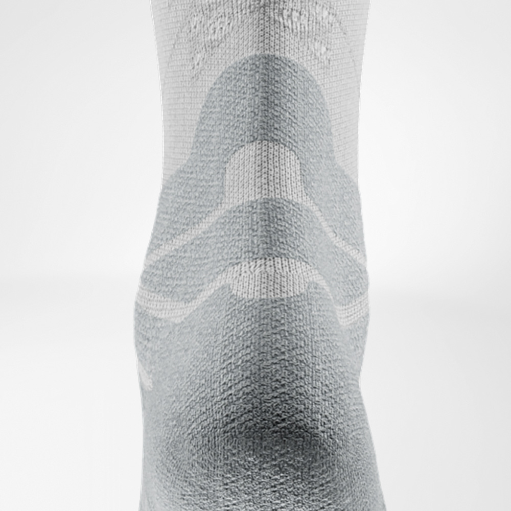 Sanfte Polsterung schützt gezielt die Achillessehne. Detailaufnahme des Achilles-Komfortpolsters der weißen Run Performance Socks zur Entlastung der Achillessehne.