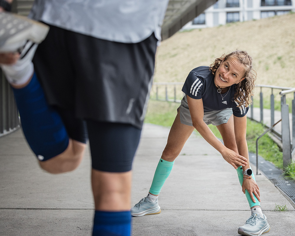 Profiter de l'entraînement de manière détendue et colorée - Run Performance Compression Socks rose Coureuse avec des chaussettes de course violettes s'appuie contre un mur dans la vieille ville de Lisbonne