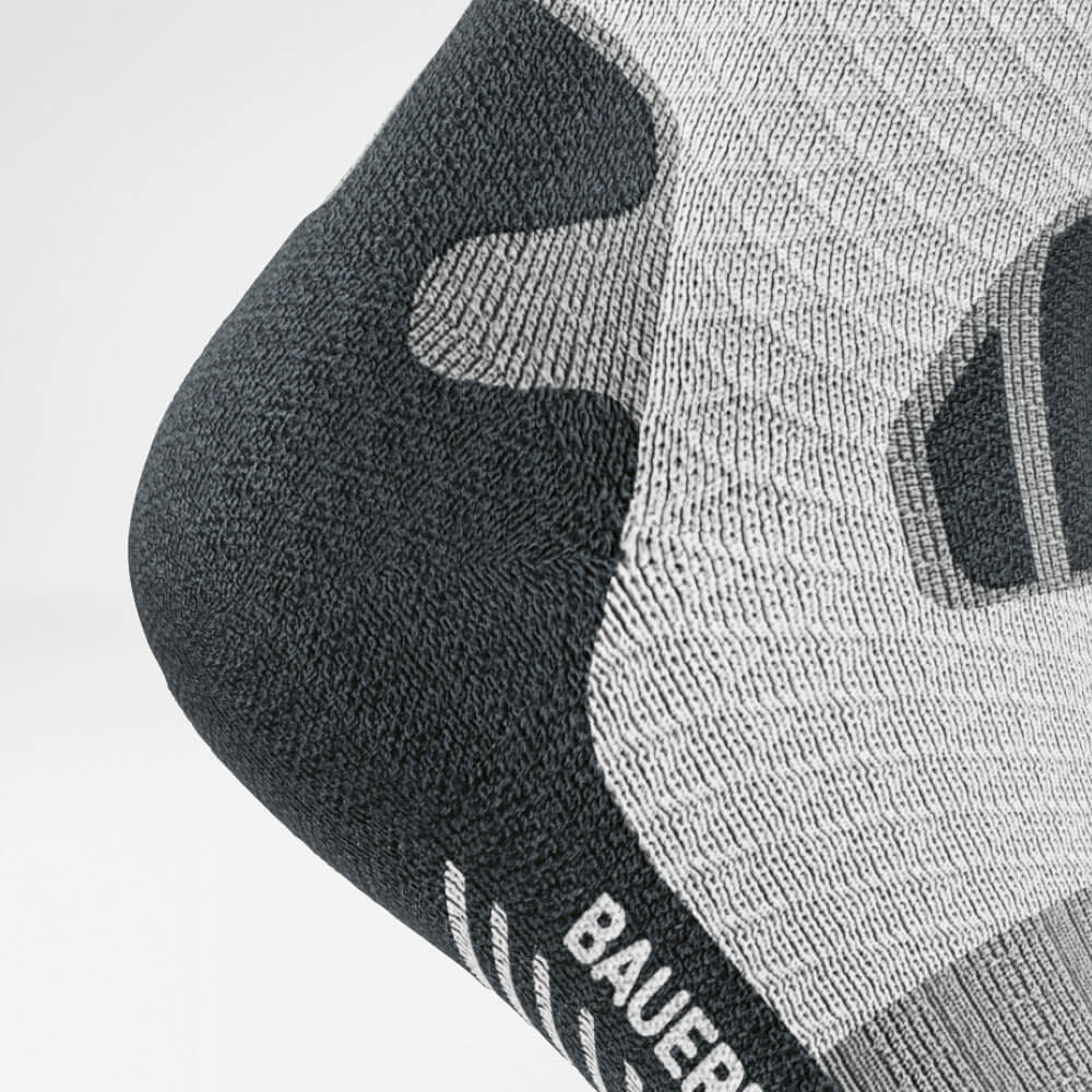 Vue en détail du talon des chaussettes de course sur sentier gris-blanc