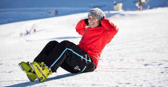 De bonne humeur pour l'aventure sur les pistes : Andrea Limbacher montre ses exercices de gymnastique préférés pour le ski Skieuse en veste rouge fait un sit-up dans la neige