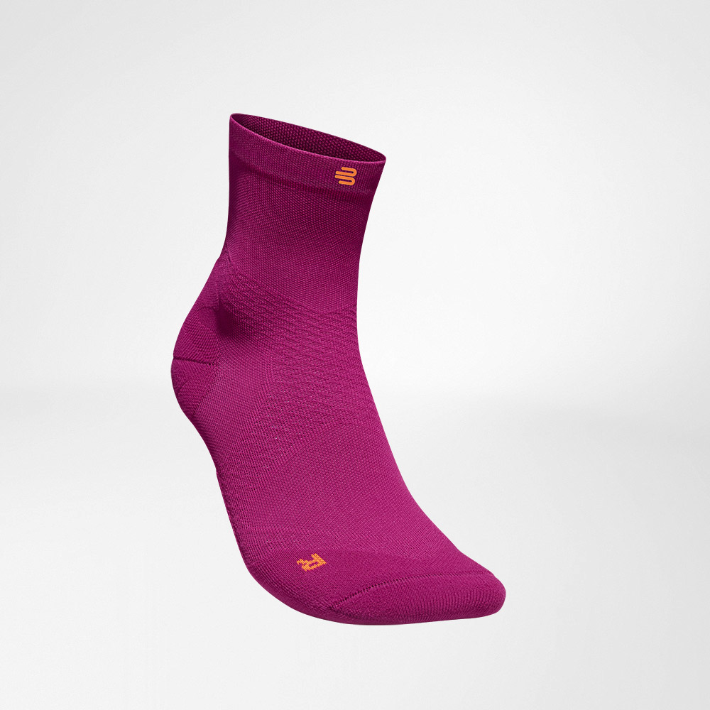Vue de côté avant des chaussettes de course roses tricotées mi-longues et aérées