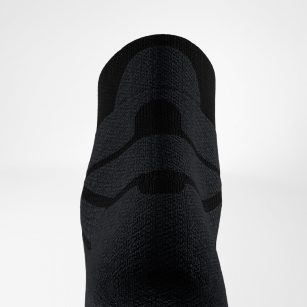 Fokus auf den Achillessehnenschutz der schwarzen Run Performance Low Cut Socks Nahaufnahme der Rückseite einer schwarzen Sportsocke mit deutlich erkennbarer, strukturierter Polsterung im Bereich der Achillessehne zur Dämpfung und Stabilisierung beim Laufen.