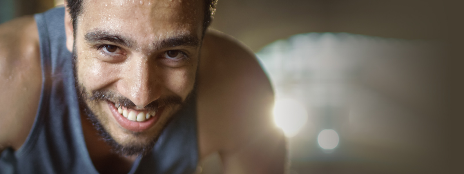 Tabata Training: Grund zur Freude, wenn Du es durchziehst Sportlicher Mann mit Bart blickt lächelnd und verschwitzt den Betrachter an