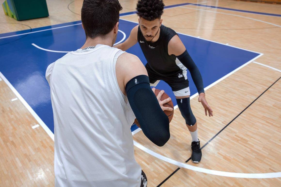 deux joueurs de basket-ball sur le terrain deux joueurs de basket-ball jouent pour un ballon et portent une manche de bras et une genouillère