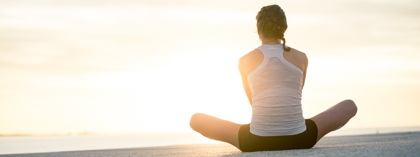 Respirer en courant Coureuse assise en tailleur vers le soleil sur le sol