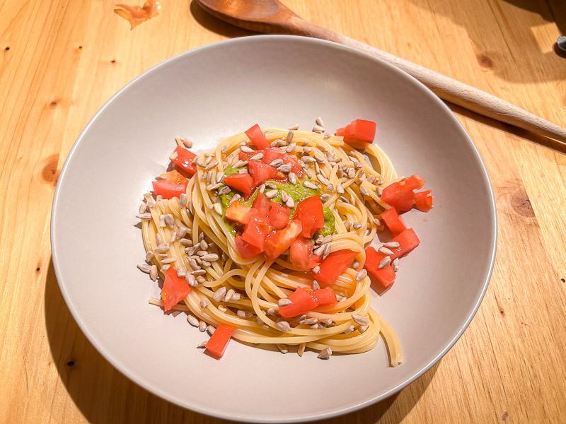 Pasta mit Tomaten und Sonnenblumenkernen als gesunde Kohlenhydratquelle für Carbo-Loading. Ein Teller mit Spaghetti, frischen Tomaten und Sonnenblumenkernen, ideal für eine kohlenhydratreiche Mahlzeit am Abend vor dem Halbmarathon.