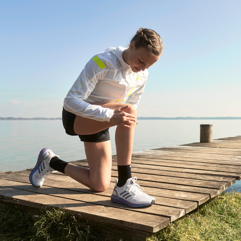 Falls Du einen Schmerz im Knie spürst, halte besser kurz an und schau nach Läuferin Anna Hahner kniend am Steg hält sich das Knie