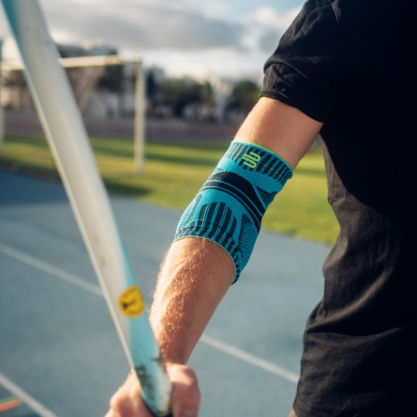 Bande de coude en surfant Femme sur la plage avec une planche de surf sous le bras portant une bande de sport pour le coude