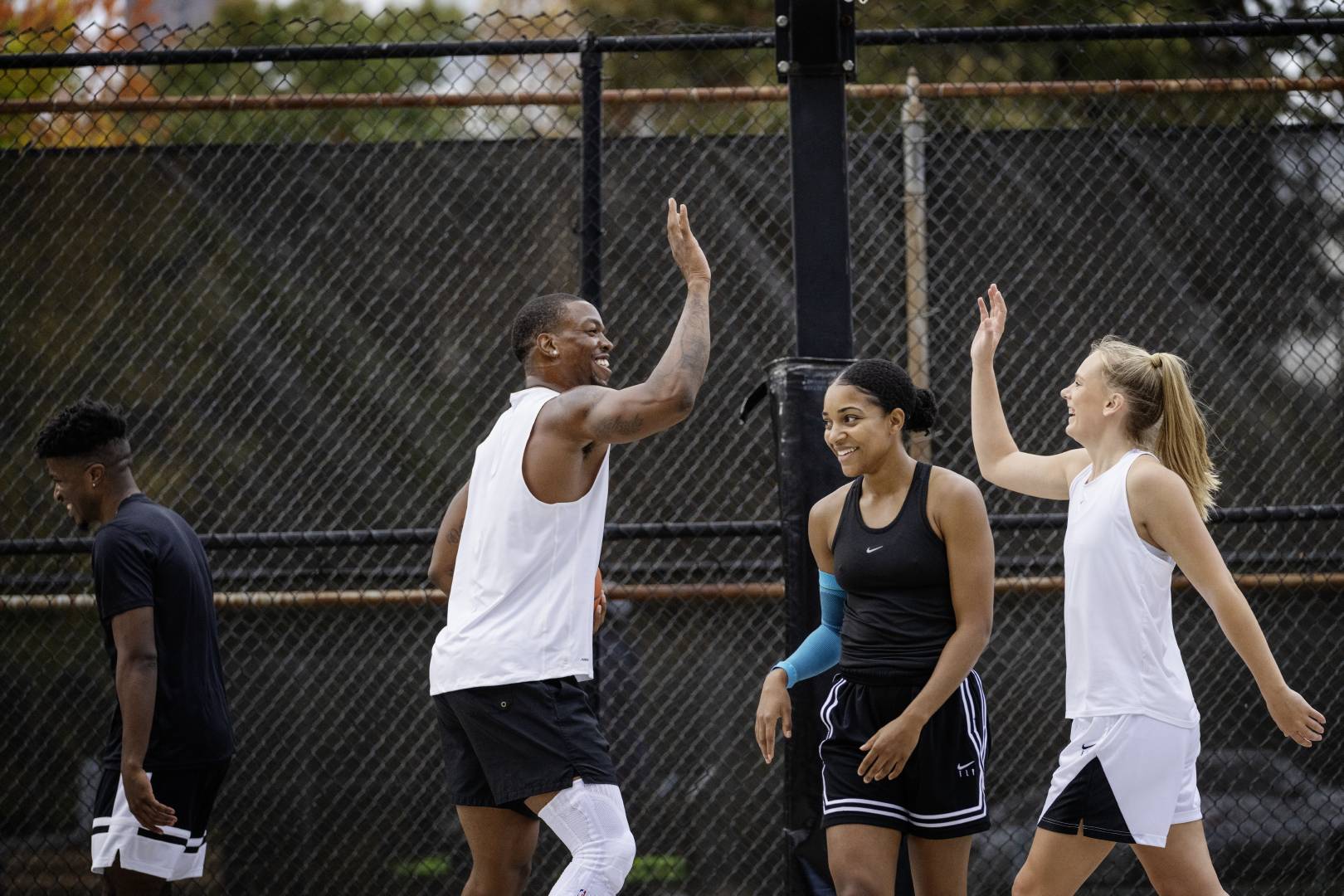 Les joueurs de basketball se réjouissent et se tapent dans les mains Deux basketteurs en tenue blanche se tapent joyeusement dans les mains tandis que leurs adversaires en noir regardent dans différentes directions