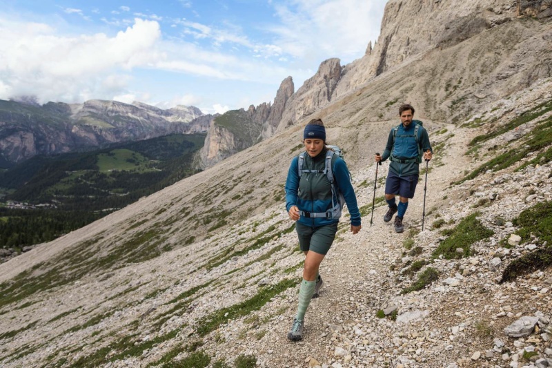Avec le bon équipement, la randonnée en montagne devient une aventure fascinante Une femme et un homme marchent sur un sentier de montagne entouré de rochers et portent un sac à dos, bâtons de randonnée télescopiques et de longues chaussettes de marche