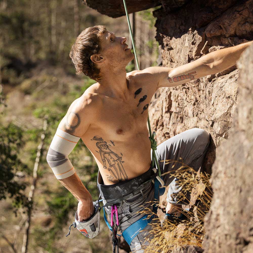 Ein Mann greift während des Kletterns in einen Chalk-Bag.