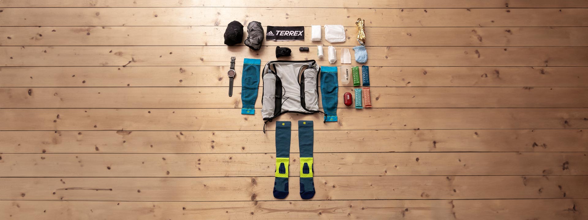 Vue d'ensemble de l'équipement de Trail Run L'équipement nécessaire de Trail Run est disposé à plat sur un sol en bois