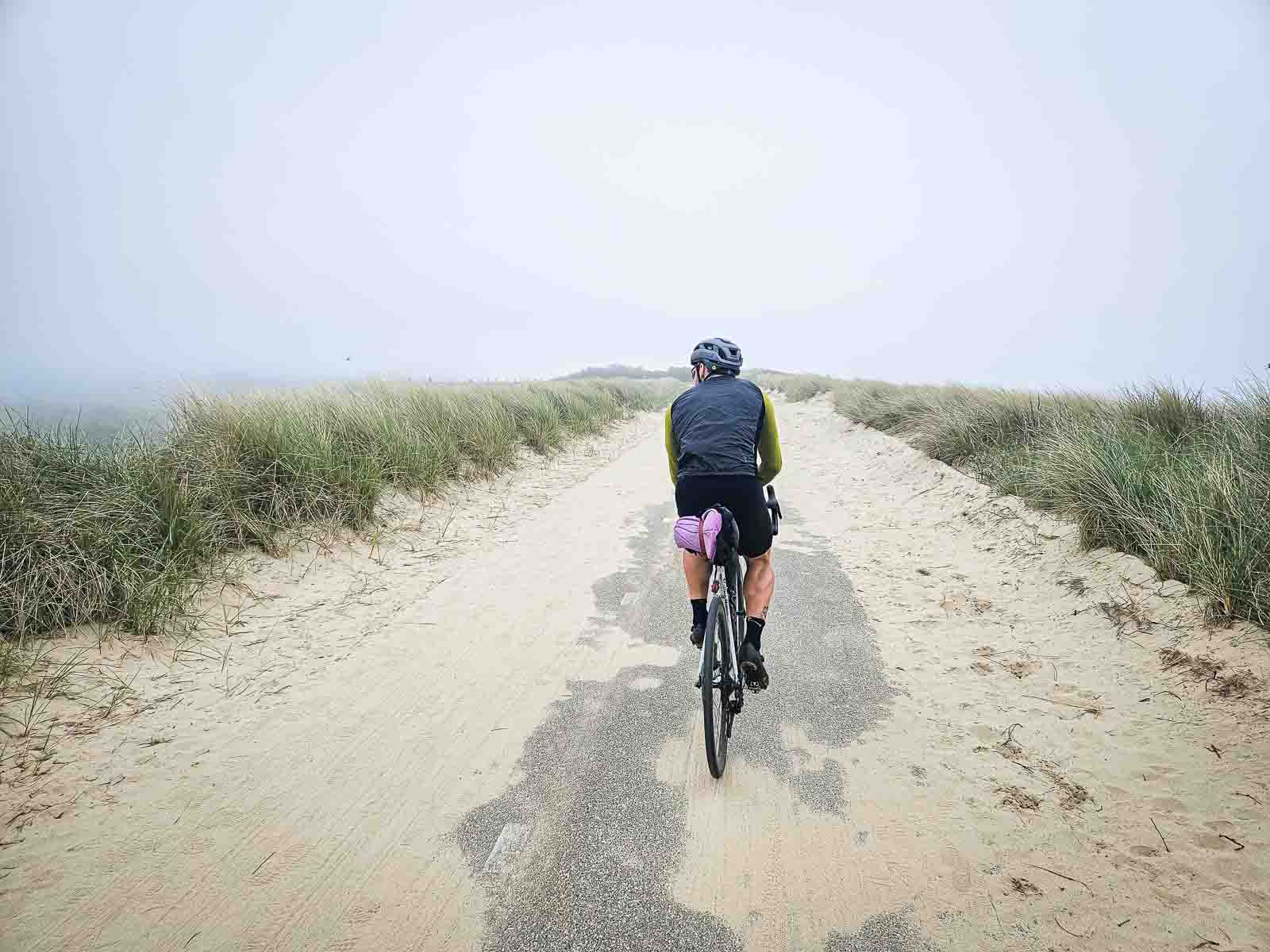 Cycliste sur une route de dunes sableuse. Un cycliste roule sur une belle route de dunes partiellement couverte de sable.