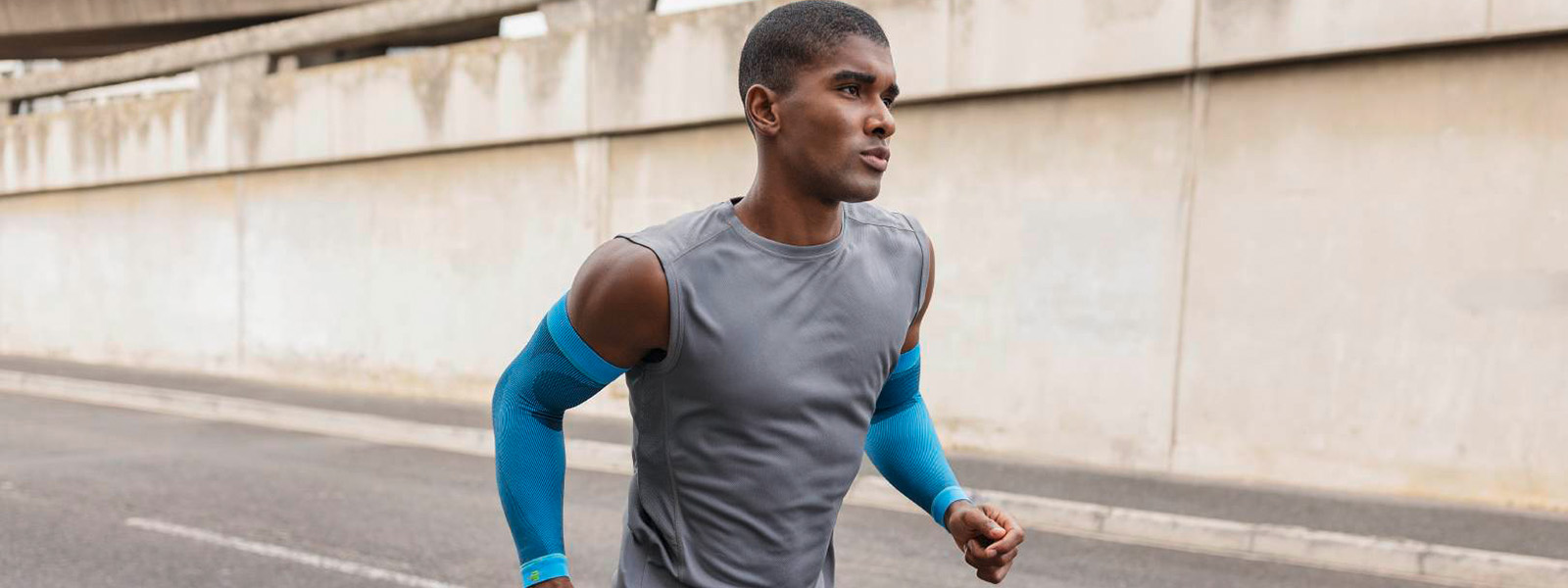Sports Compression Sleeves Arm rivera Running Un homme fait du jogging en ville et porte des manchons de compression bleus