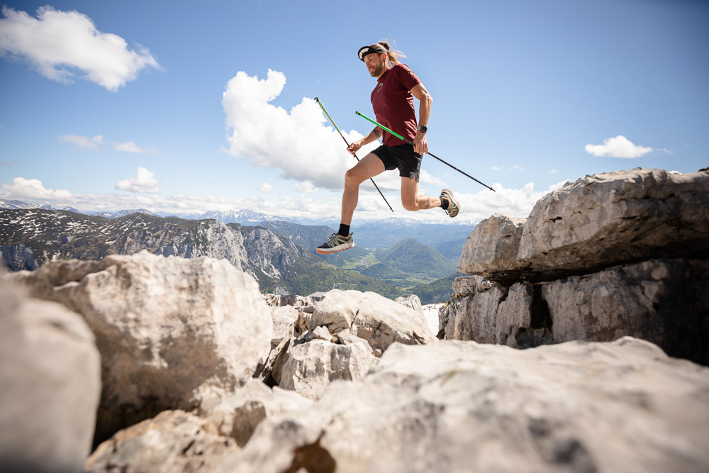 Lord Jens Kramer beim Trailrunning mit Stöcken beim Sprung über Felsen im Hochgebirge
