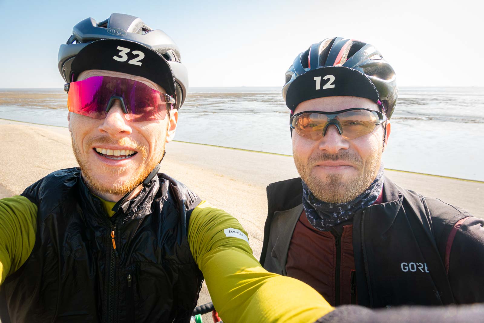 Deux cyclistes au bord de la mer rient à la caméra Deux cyclistes font un selfie d'eux-mêmes devant un panorama de plage en riant.