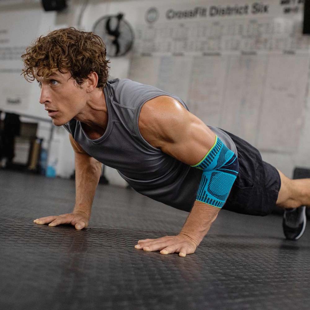 Ellenbogenbandage beim Fitness Junger Mann macht Push-ups in einem Fitnessstudio und trägt dabei eine Ellenbogenbandage in rivera